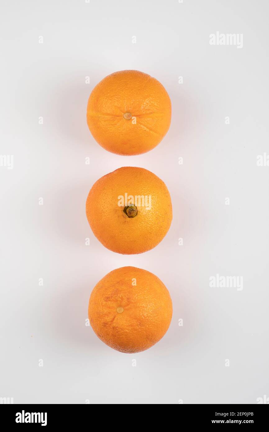 Three whole fresh oranges placed on white table Stock Photo
