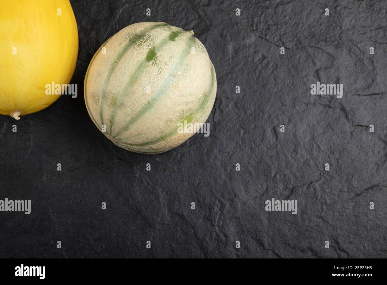Fresh ripe yellow and green melons on black surface Stock Photo Alamy