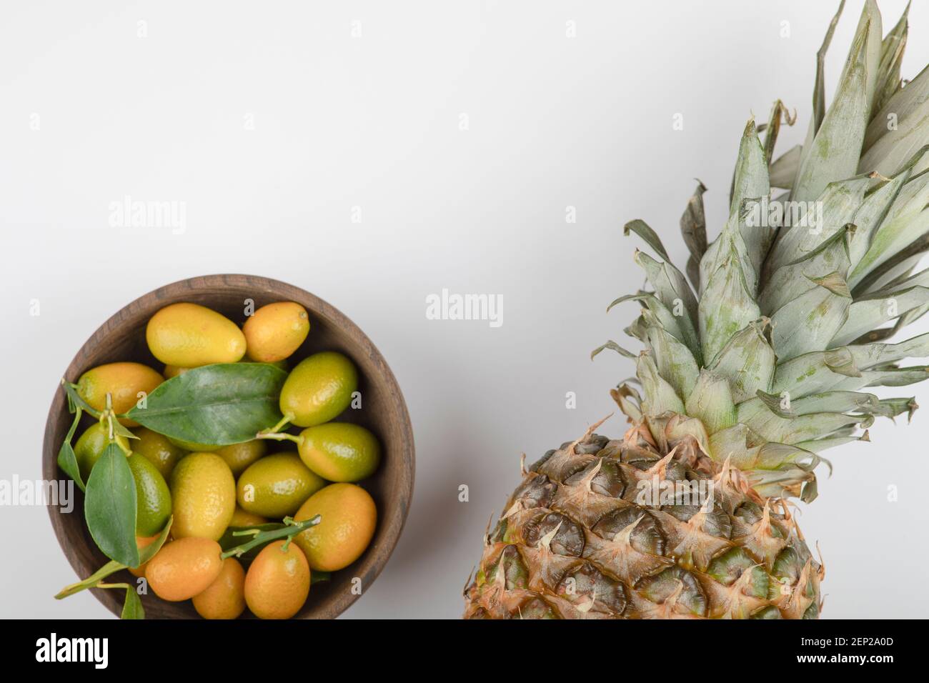 Wooden bowl of yellow kumquats and pineapple on white background Stock ...