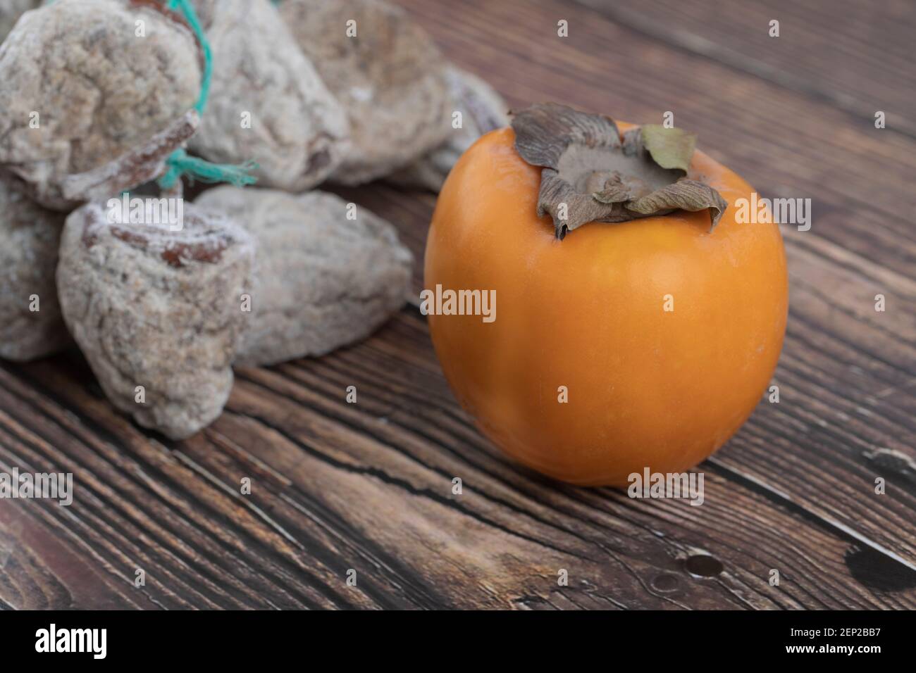 Tasty fuyu persimmon and dried persimmons on wooden surface Stock Photo