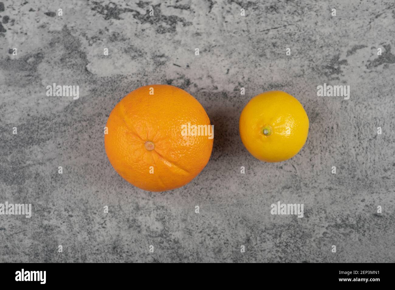 One fresh orange fruit with whole lemon on stone table Stock Photo
