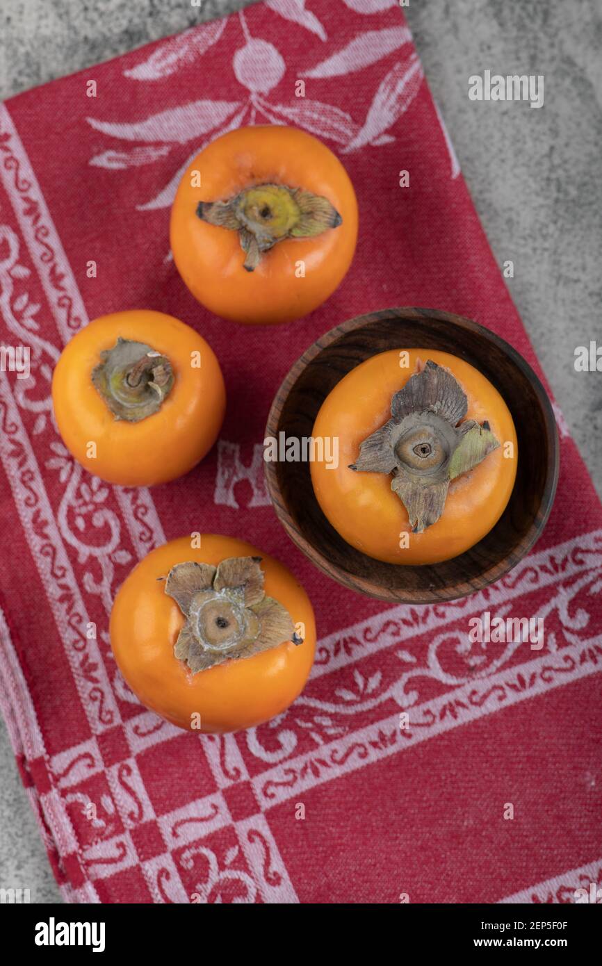 Delicious fuyu persimmon fruits on top of red tablecloth Stock Photo