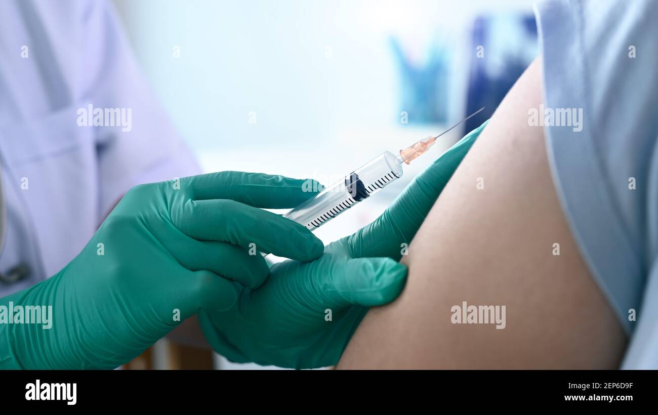 Close up view of doctor holding syringe and giving injection to woman ...
