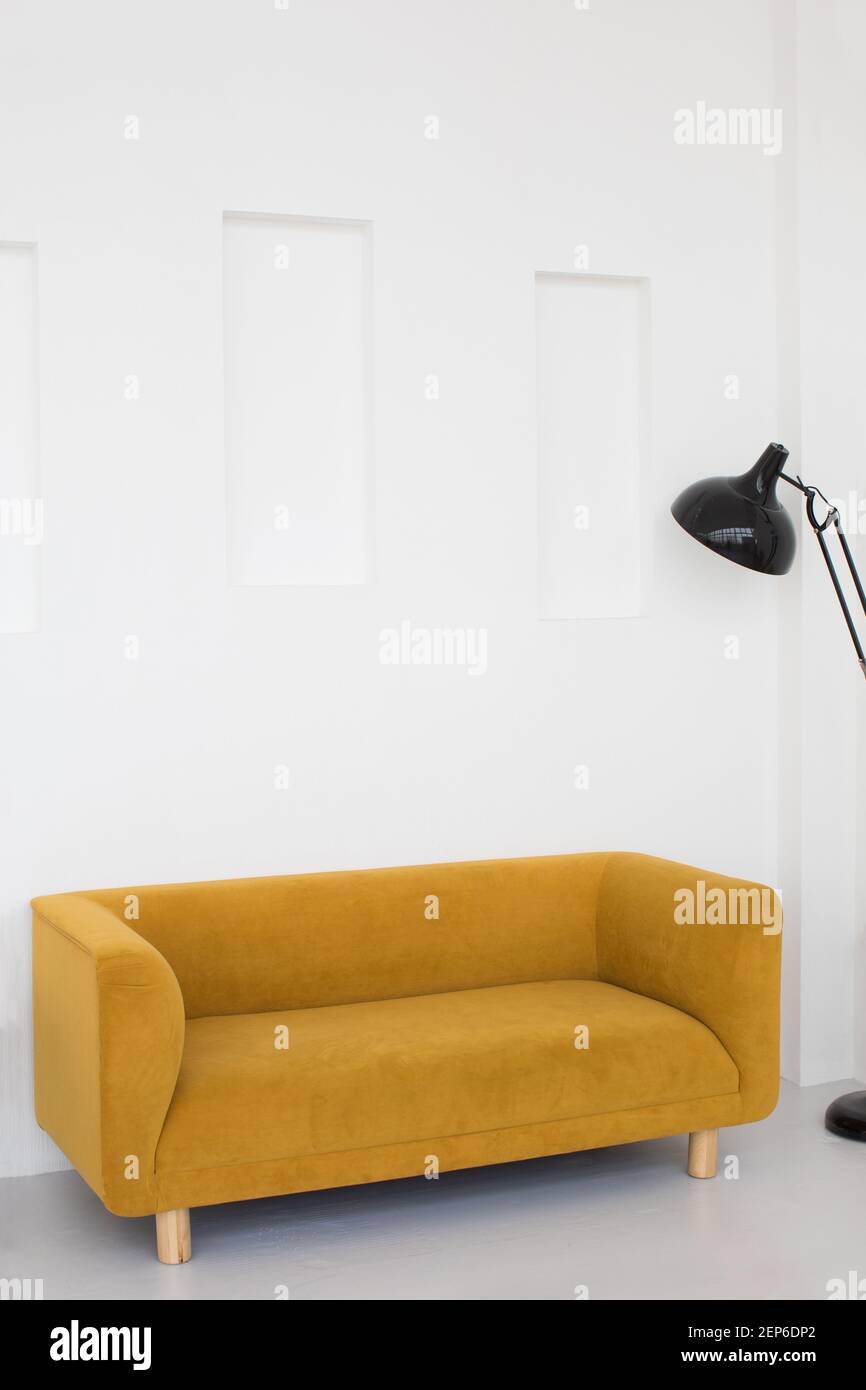 Comfortable yellow couch and floor lamp placed in living room with white walls in minimal style Stock Photo