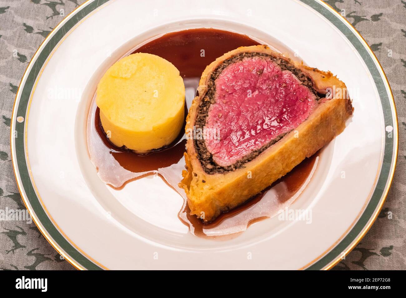Slice of Fillet of Beef Wellington with Red Wine Gravy and Mashed Potatoes on a Plate Stock Photo