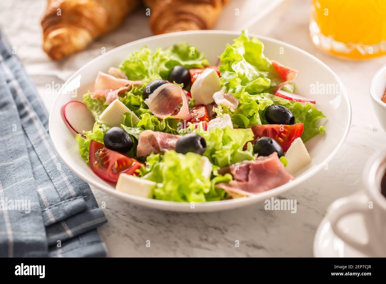 Healthy salad in a bowl with olives, raddishes, tomato, cheese and lean ham served for breakfast Stock Photo