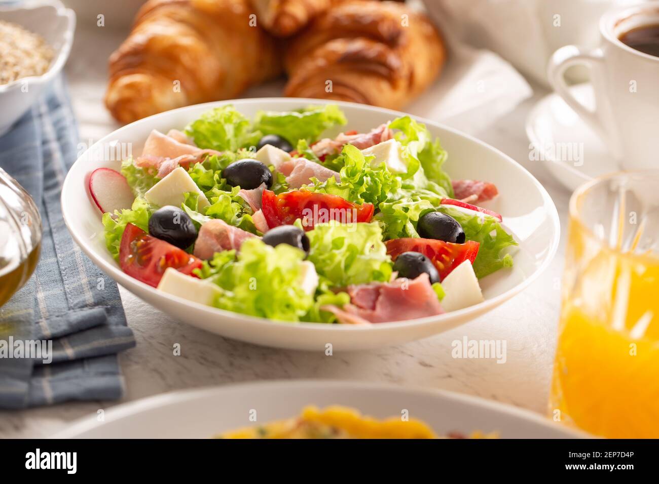 Healthy salad in a bowl with olives, raddishes, tomato, cheese and lean ham served for breakfast Stock Photo