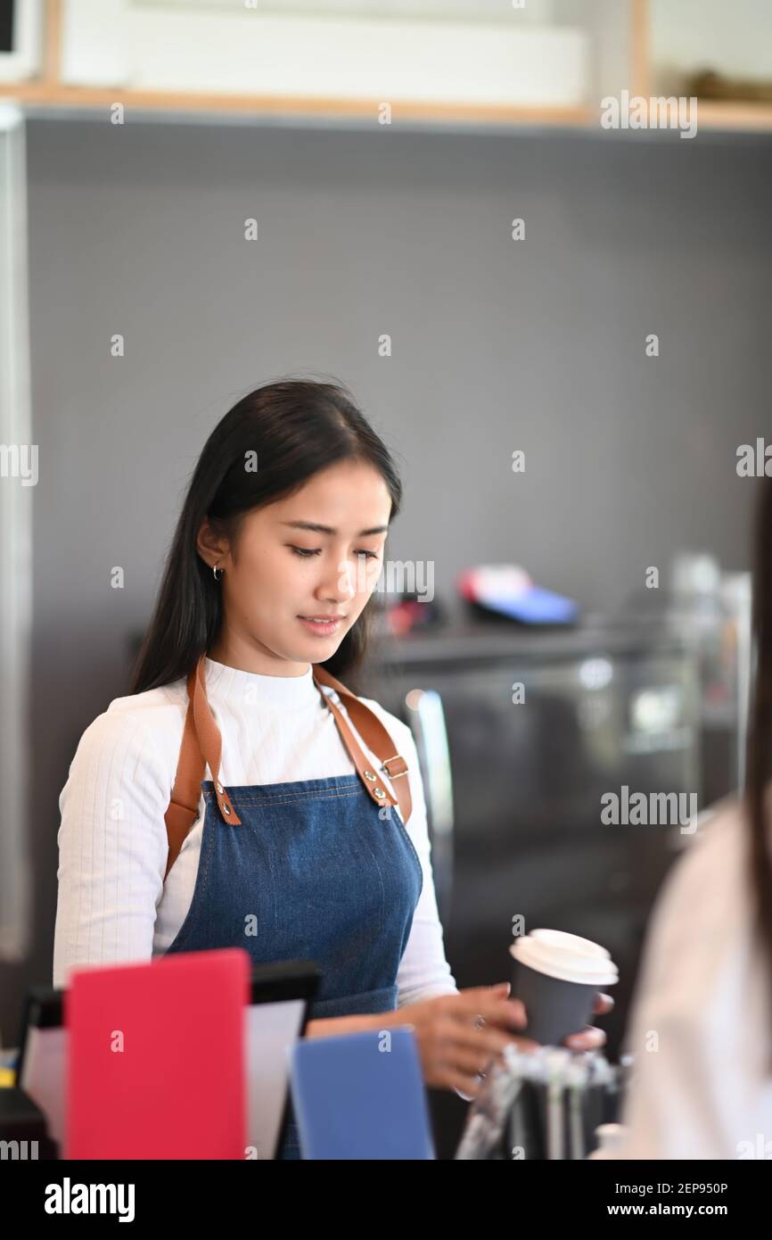 Cheerful barista giving paper cups of coffee to customer at counter bar ...