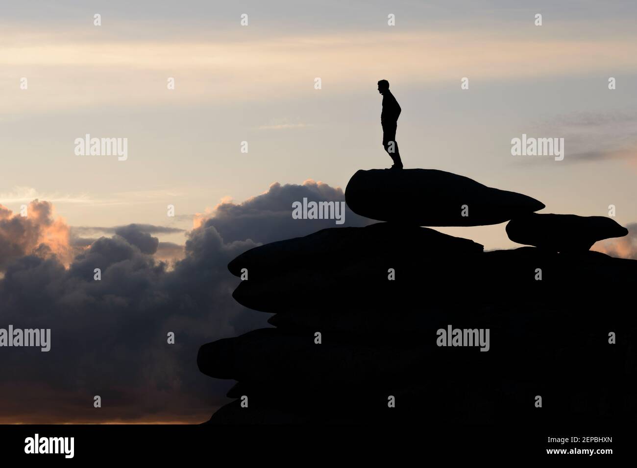 A lone man surveying the landscape stood atop a rocky outcrop on Stowe's Hill, Cornwall. Stock Photo