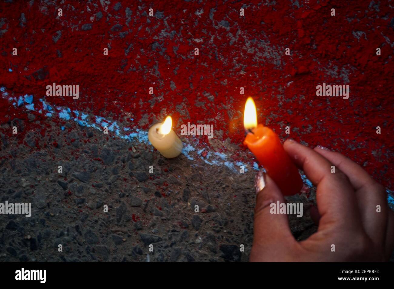 A hand of a woman is seen as she lights candles in memory of those who ...