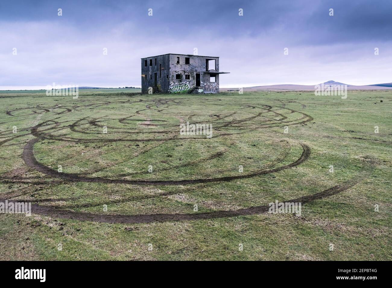 Vehicle tyre marks in the grass left by joy riders in front of the derelict control tower on the disused WW2 RAF Davidstow Airfield on Bodmin Moor in Stock Photo