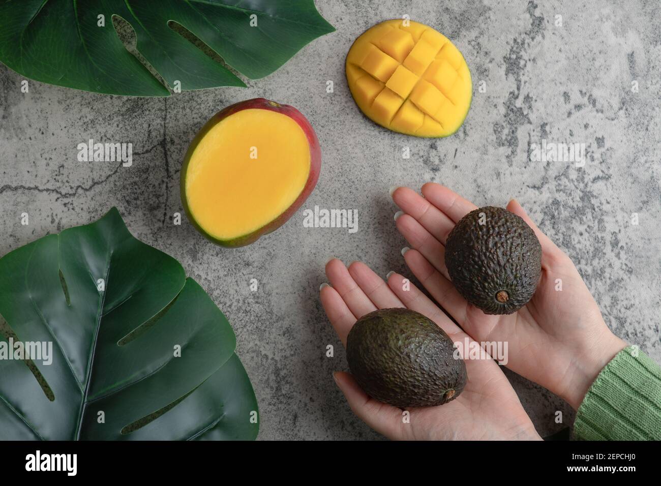 Female hands holding ripe avocados on marble surface Stock Photo - Alamy