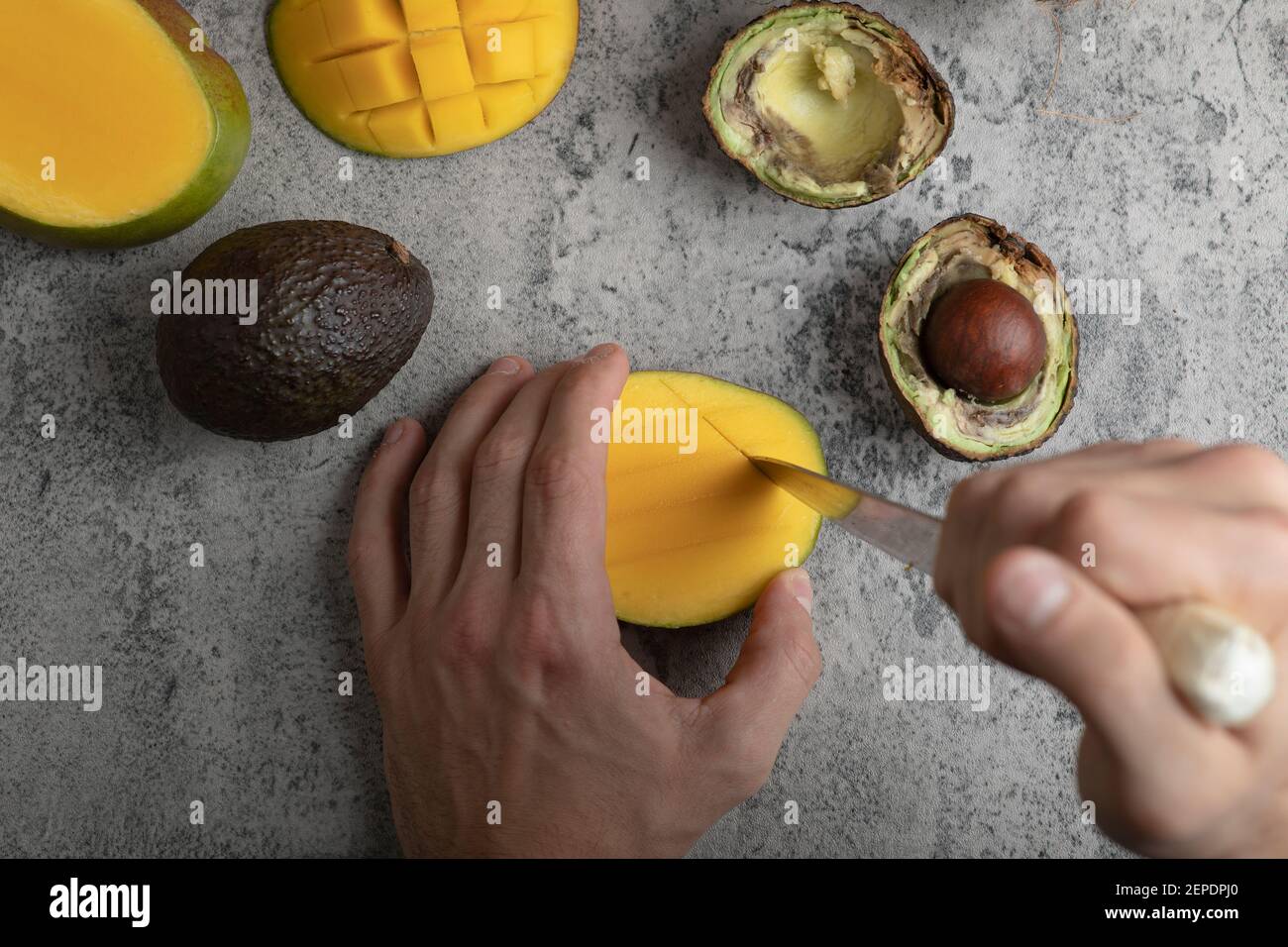 Male hands cutting mango into the cubes on marble surface Stock Photo