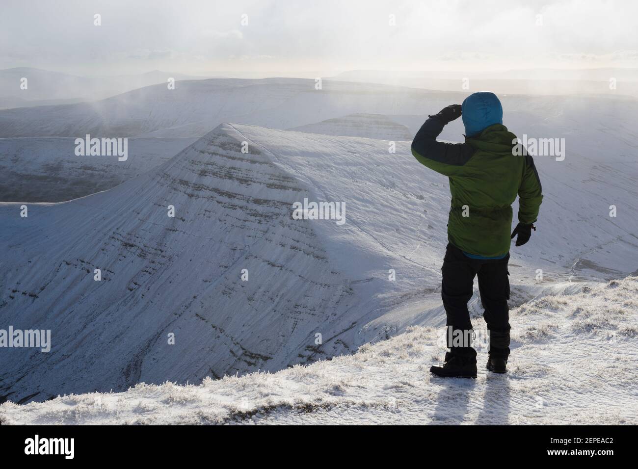 A male hiker admires the view of snow covered Cribyn in the Brecon Beacons, Wales. Stock Photo