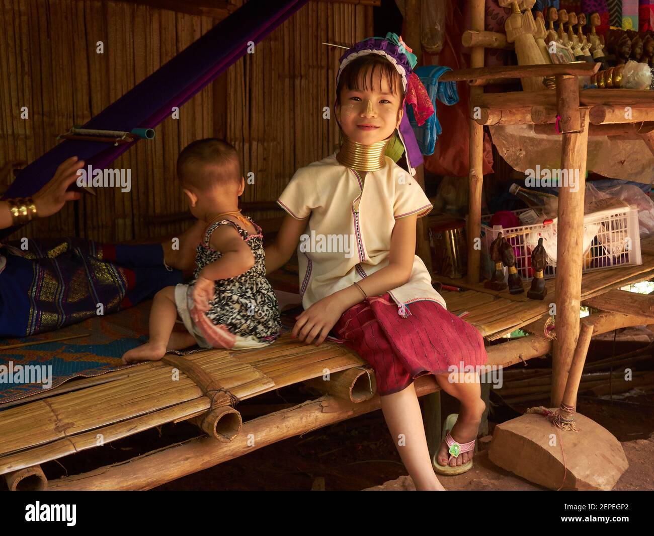 a little girl from Karen or Long Neck tribe playing with her younger