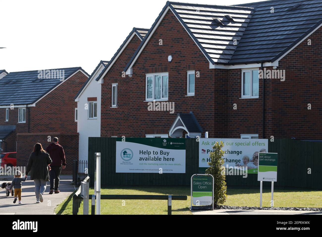 Shepshed, Leicestershire, UK. 27th February 2021. A family walk past the entrance to a new housing development. A mortgage guarantee scheme to help people with small deposits get on the property ladder is set to be announced at next week's Budget.  Credit Darren Staples/Alamy Live News. Stock Photo