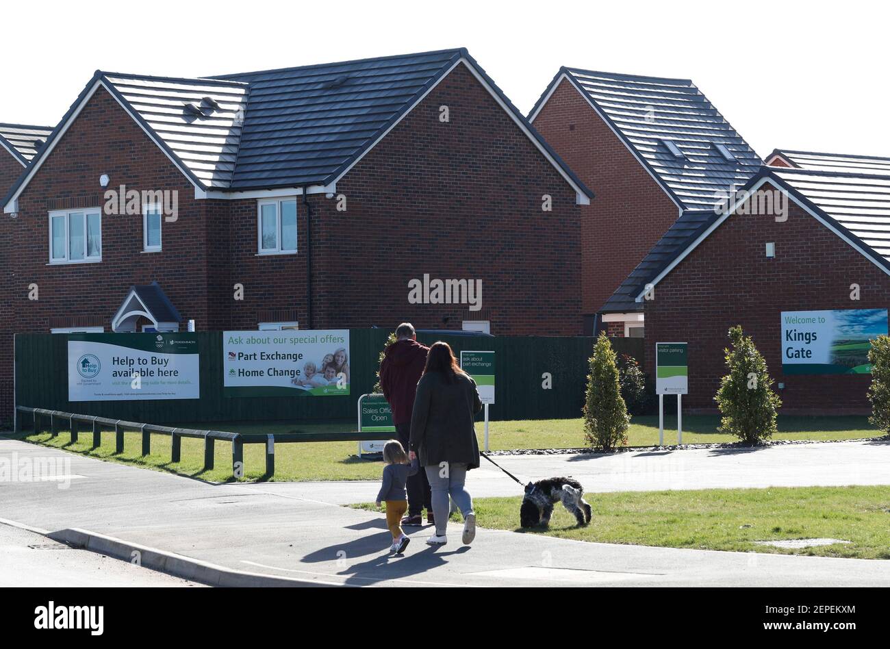 Shepshed, Leicestershire, UK. 27th February 2021. A family walk past the entrance to a new housing development. A mortgage guarantee scheme to help people with small deposits get on the property ladder is set to be announced at next week's Budget.  Credit Darren Staples/Alamy Live News. Stock Photo