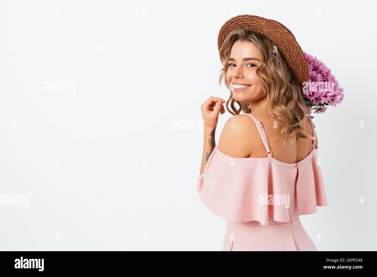 Cute young woman with bouquet fresh flowers wearing straw hat and pink ...