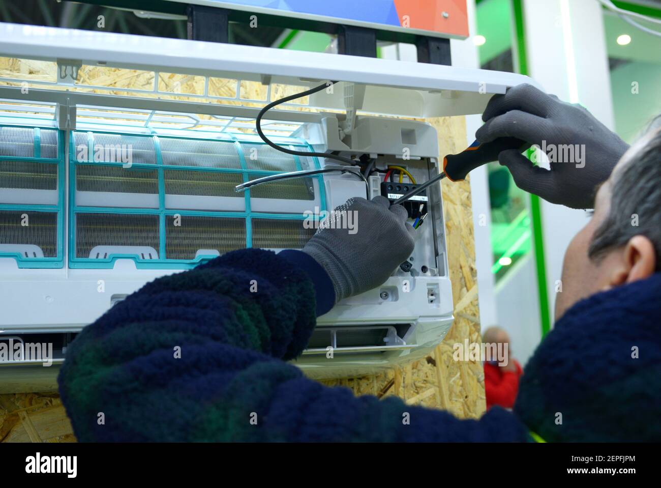 Worker hands assembling air conditioner using screwdriver Stock Photo