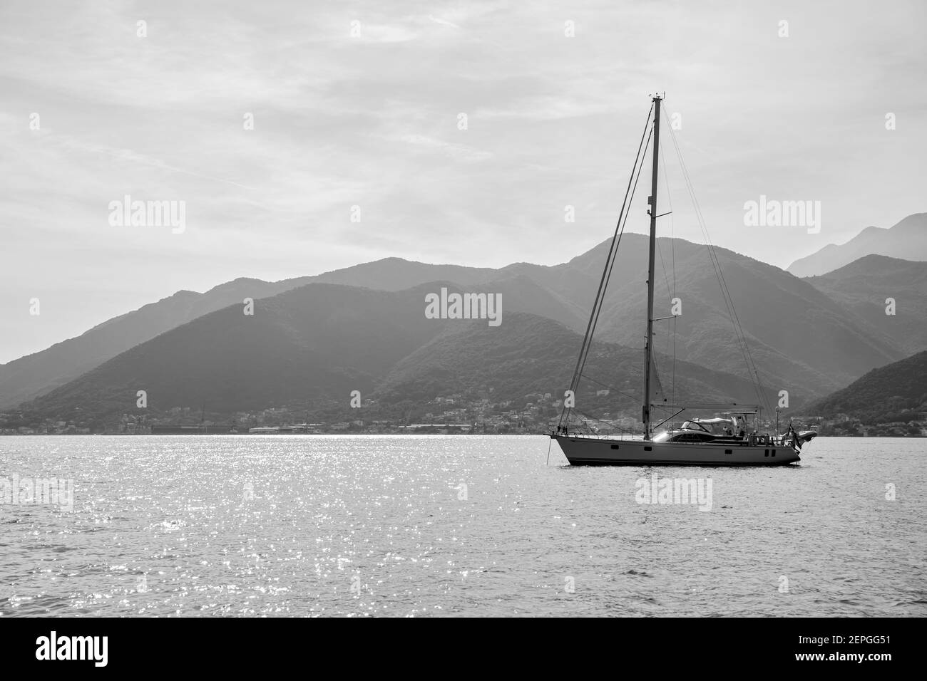 Sail yacht with tall mast in the sea off the shore. Seascape, black and white photography Stock Photo
