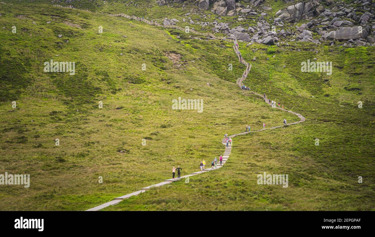 People hiking on wooden boardwalk, climbing on steps and stairs to