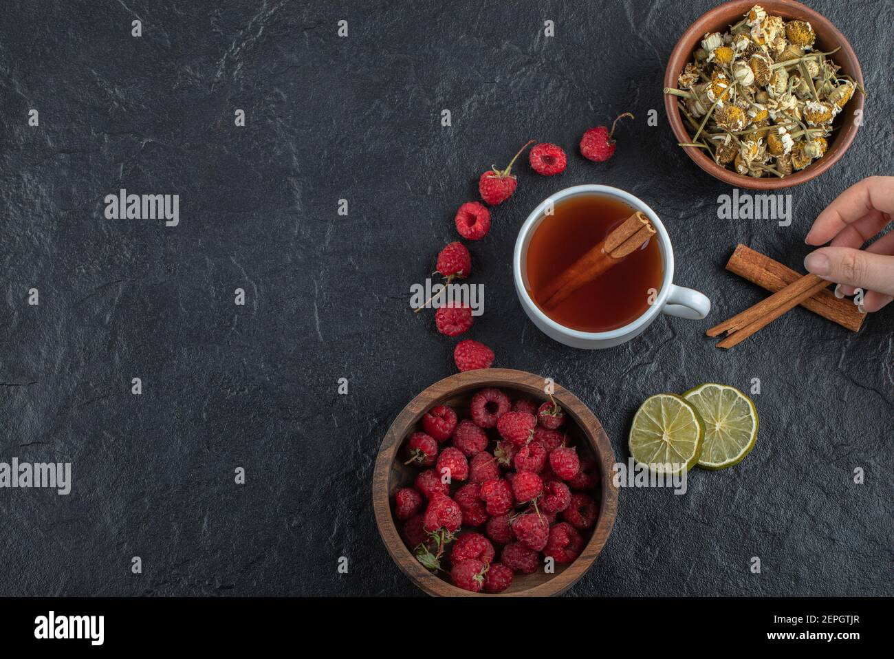 Female hand holding cinnamon on black background Stock Photo