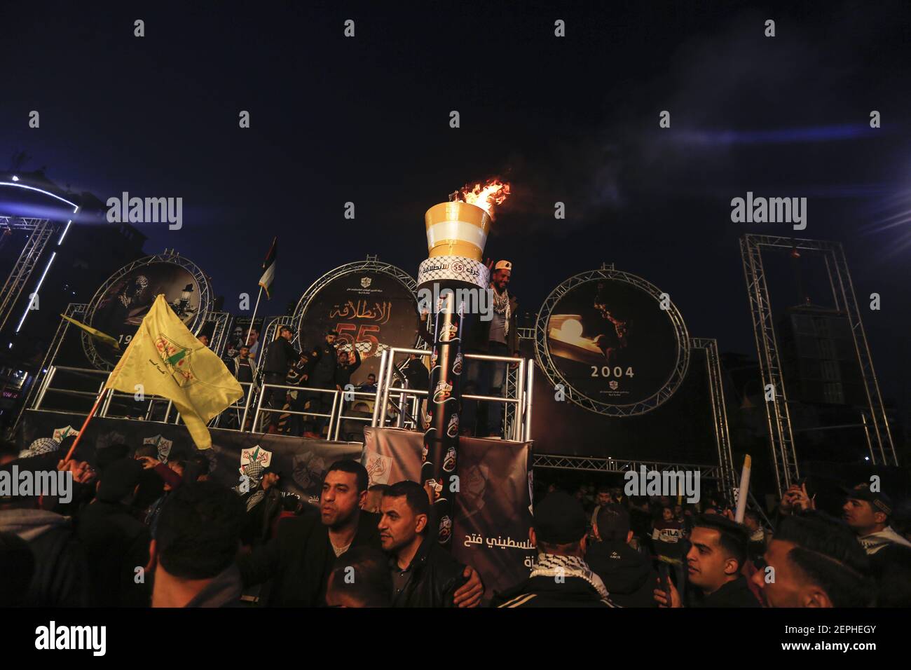 Palestinians light a torch during the celebrations marking the 55th