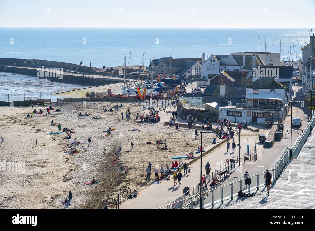 Lyme Regis, Dorset, UK. 27th Feb, 2021. UK Weather: Plenty of people were out and about enjoying unseasonably warm and sunny weather at the seaside resort of Lyme Regis this afternoon. Credit: Celia McMahon/Alamy Live News Stock Photo