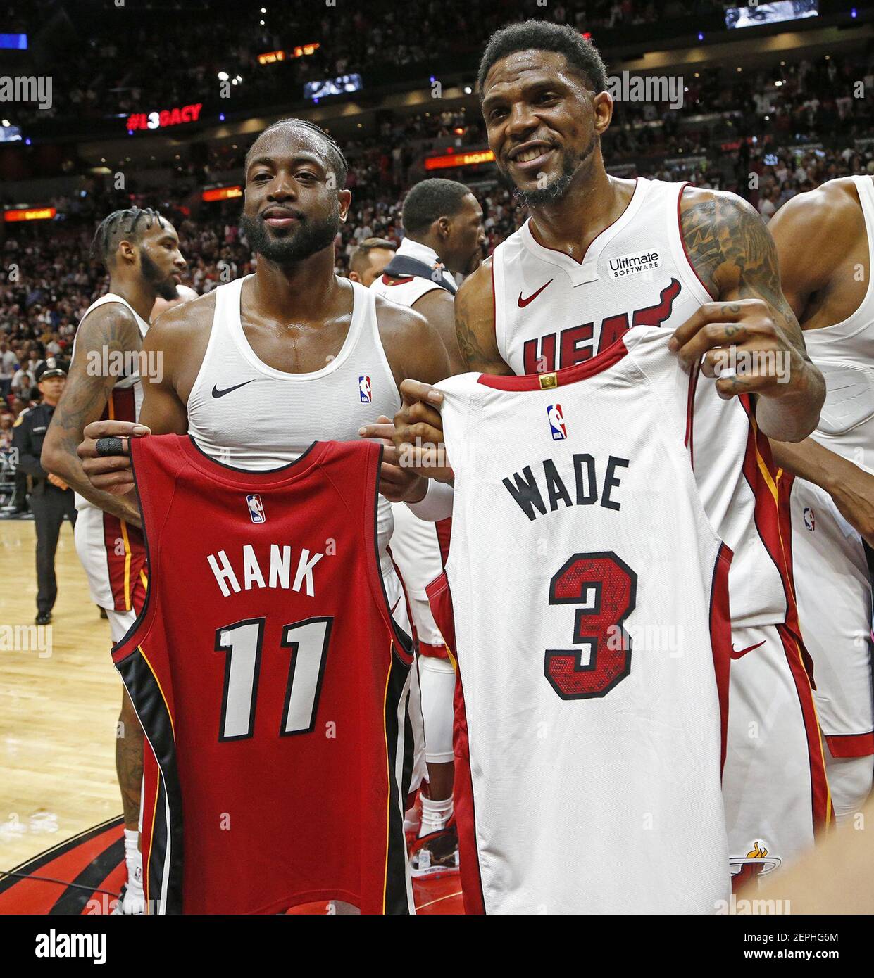 The Miami Heat's Dwyane Wade, left, holds a jersey with the number 11 that  honors his former agent Henry Thomas, who died in 2018, while teammate  Udonis Haslem, right, holds Wade's jersey