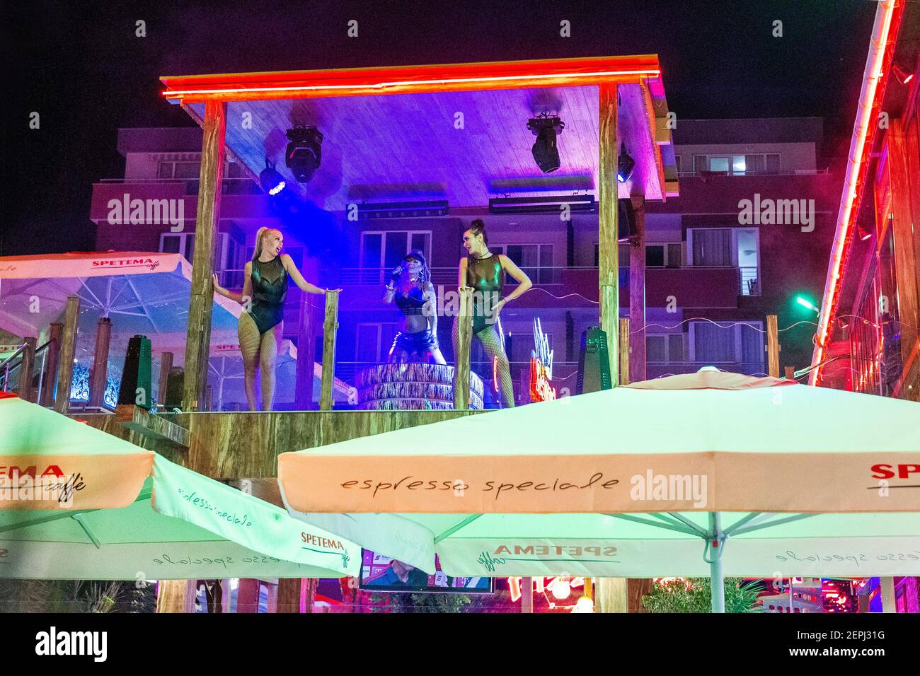 08-05-2018  Sunny beach , Bulgaria . An outdoor singer accompanied by two female dancers in bikini. On the roof of the disco Stock Photo
