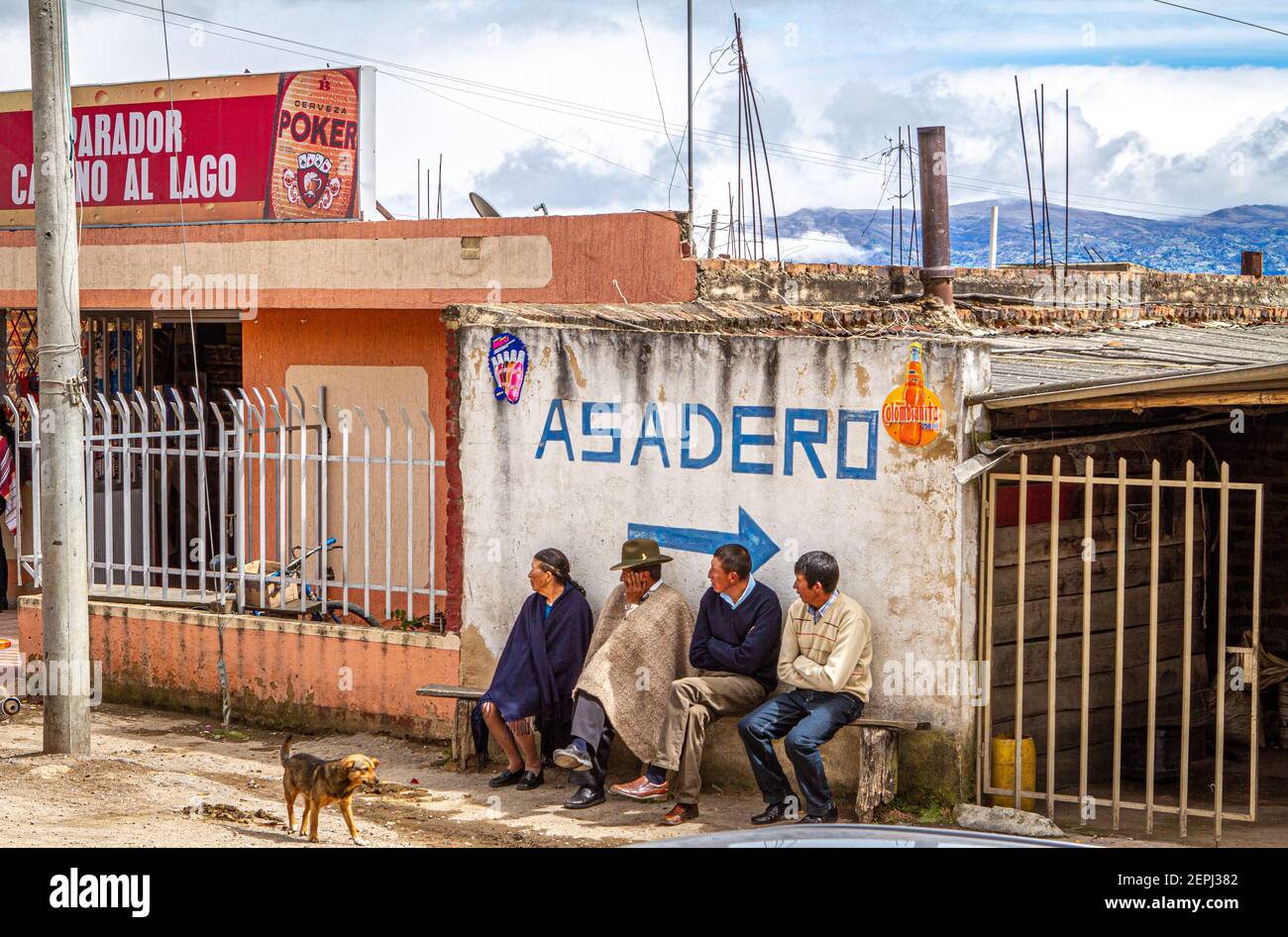 1 dog,Colombian 3 men, 1 women sitting on bench, waiting. 1 in traditional hat  poncho, Ruana. Asadero sign Boyacá Department, Colombia, South America Stock Photo