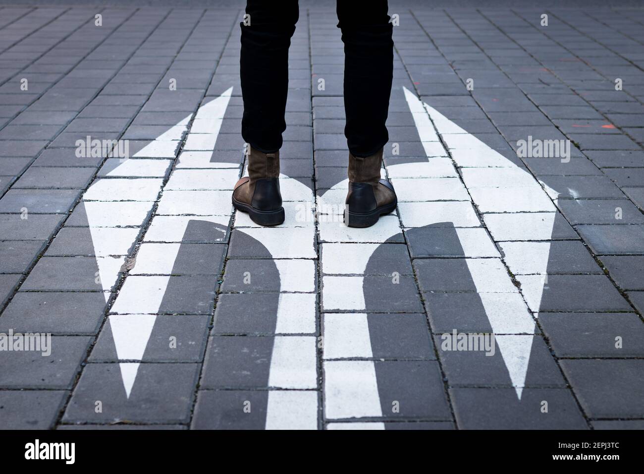 Make decision which way to go. Walking at directional sign on road. Choice concept with human legs and arrow symbol on street Stock Photo