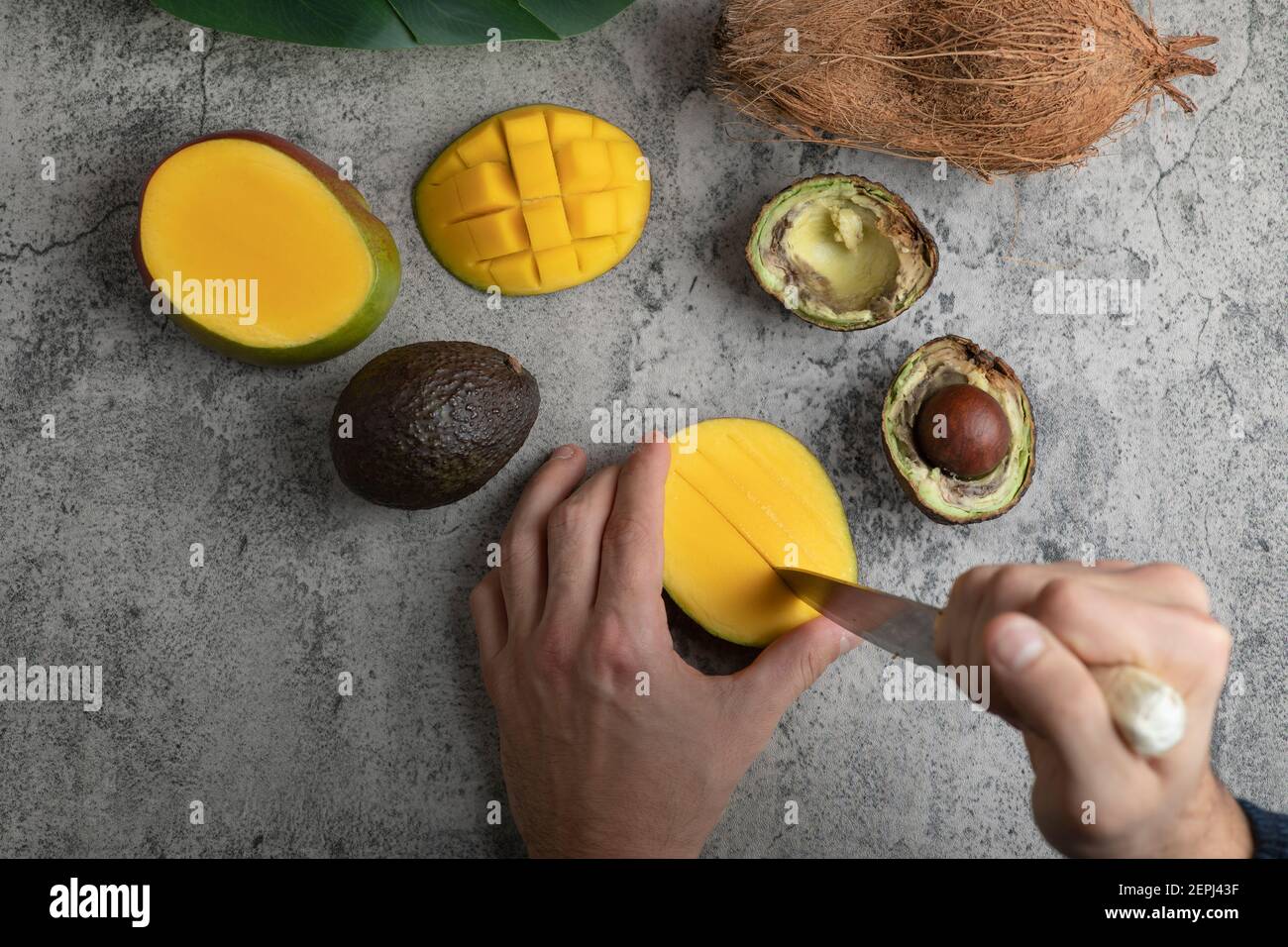 Male hands cutting mango into the cubes on marble surface Stock Photo