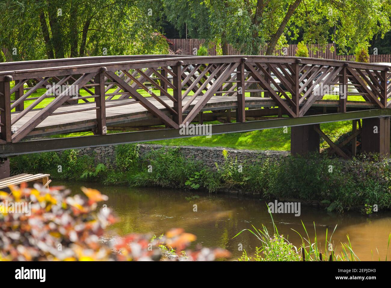 Wooden beautiful bridge over a pond in a country club in summer in sunlight Stock Photo