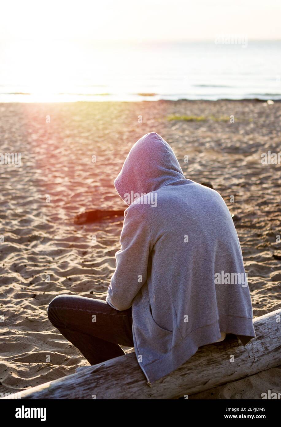 Sad and Lonely Man in a Hoodie sit on the Log at Seaside Stock ...