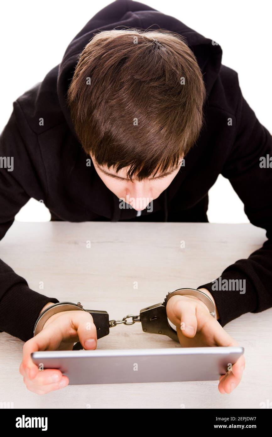 Young Man in Handcuffs hold a Tablet Computer on the Table closeup Stock Photo