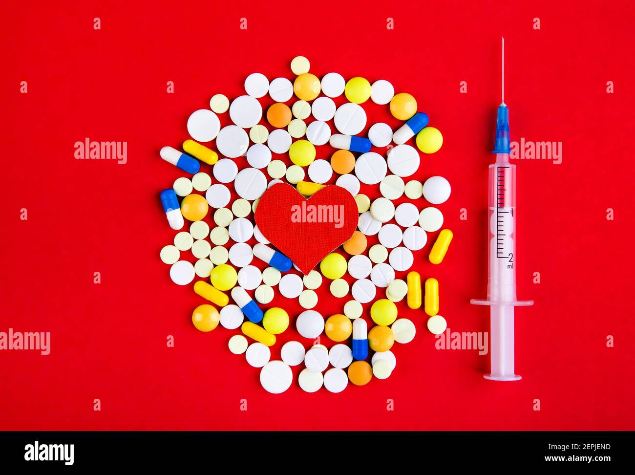 Heart Shape with a Pills and a Syringe on the Red Background Stock Photo