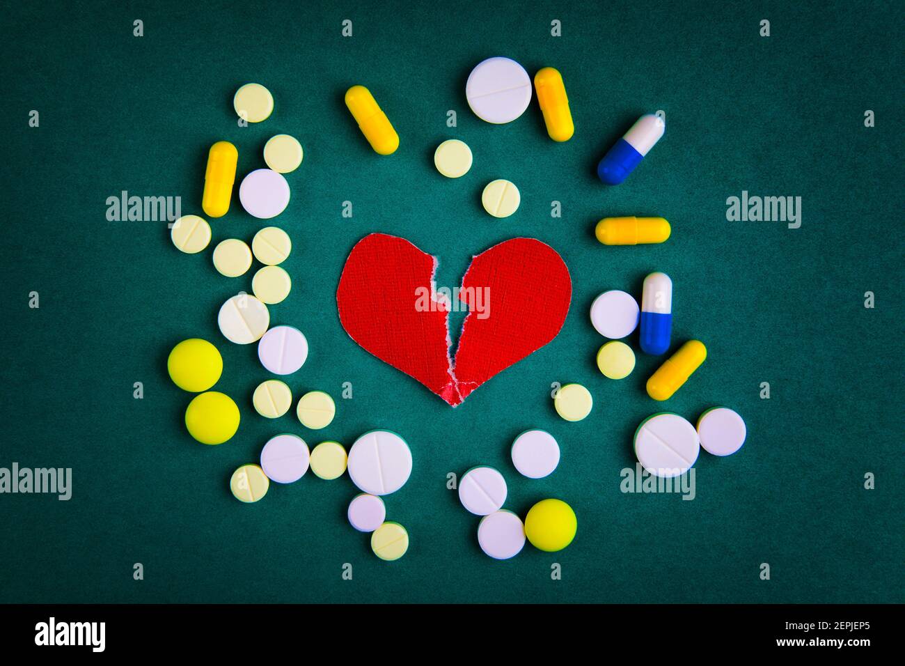 Broken Red Heart Shape with a Pills on the Green Background Stock Photo