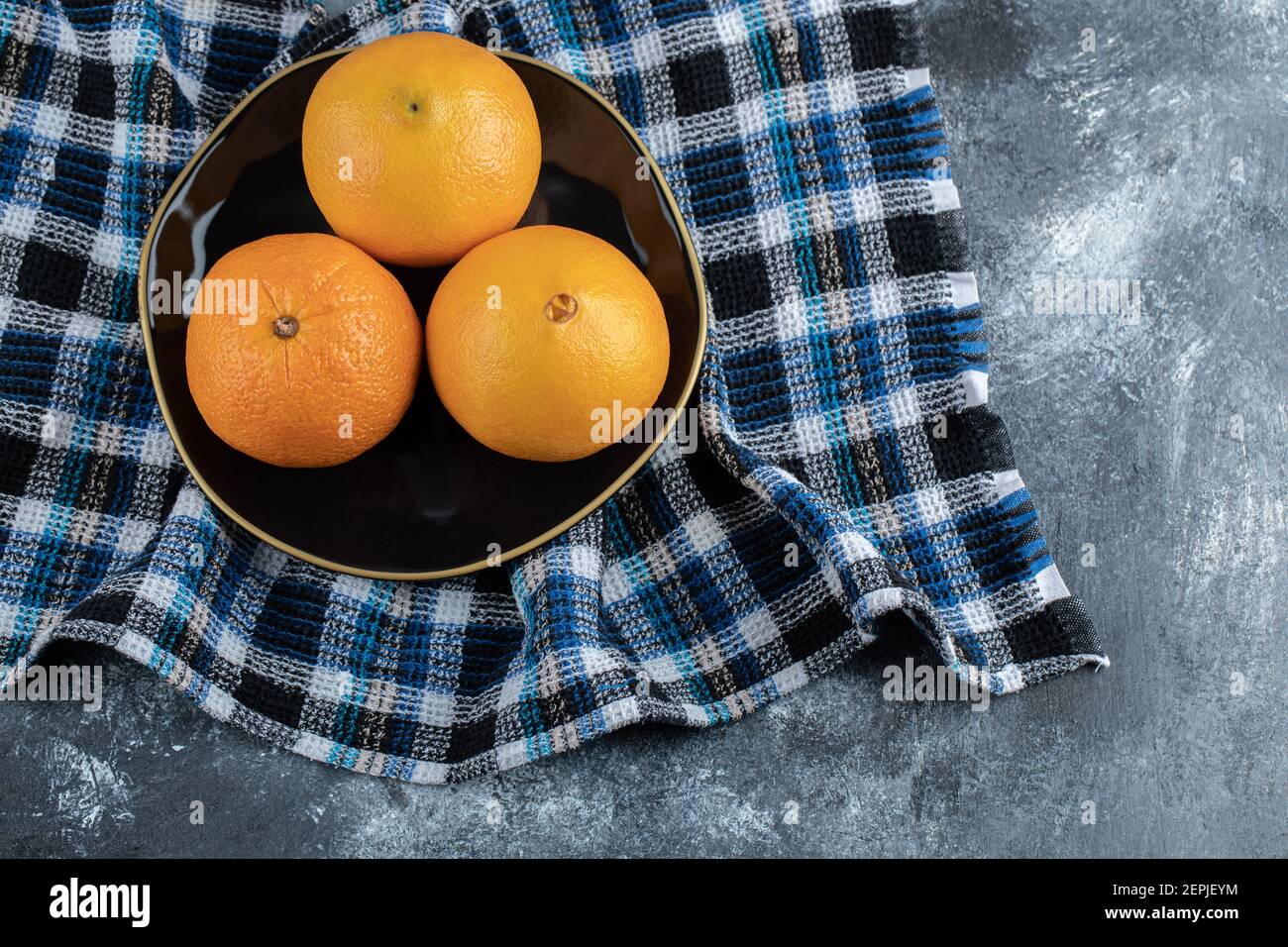 Three ripe oranges on black plate Stock Photo