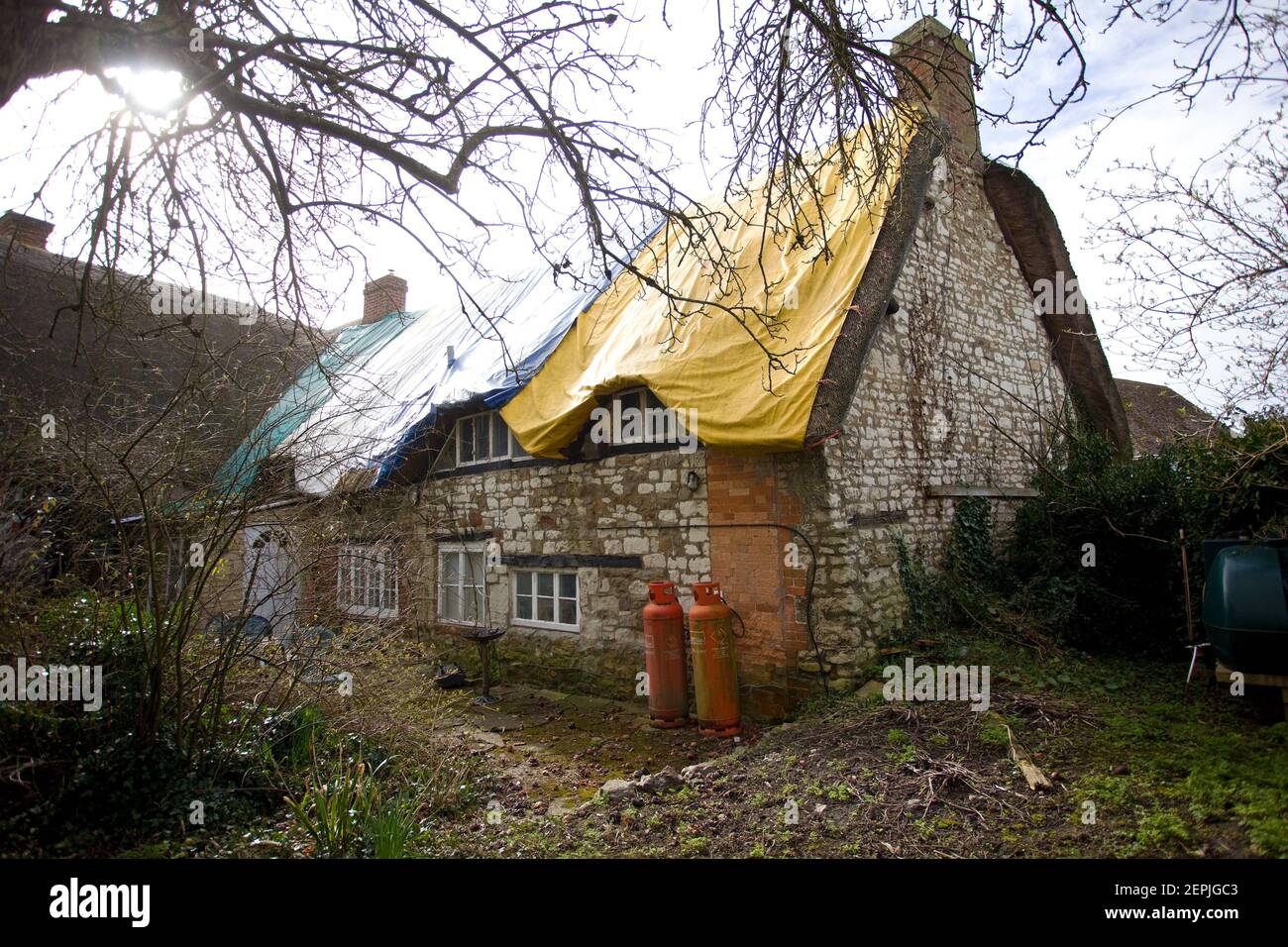 Old chalkstone cottage in need of a new thatch roof, England Stock Photo