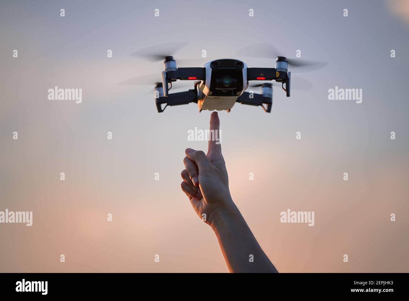 A small quadcopter model hovering in the air directly over a pointing