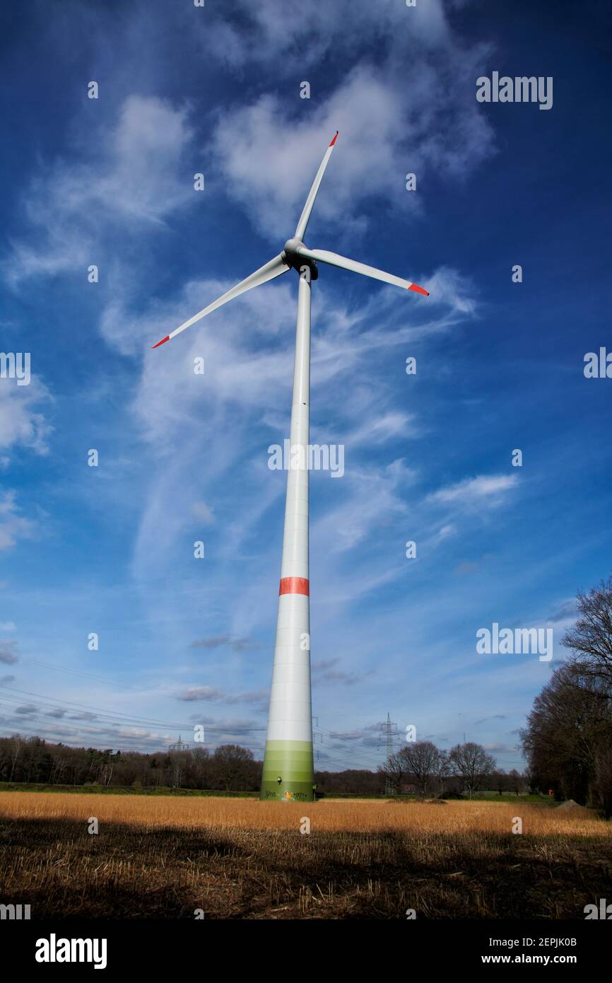 Windkraftanlage in einem Waldgebiet im Ruhrgebiet, Deutschland. Zusehen ist die ganze Windkraftanlage vor blauem Himmel mit einem schoenen Wolkenbild. Stock Photo