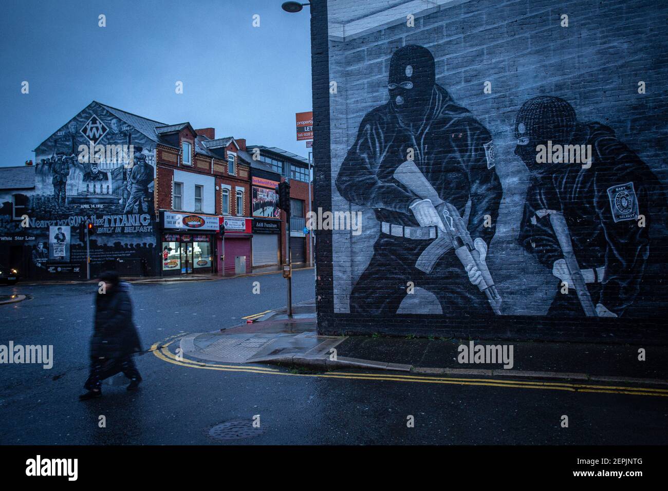 BELFAST, NORTHERN IRELAND - February, 23: A woman walks past a Loyalist paramilitary mural on the Newtownards road on February 23, 2021 in Belfast. Stock Photo