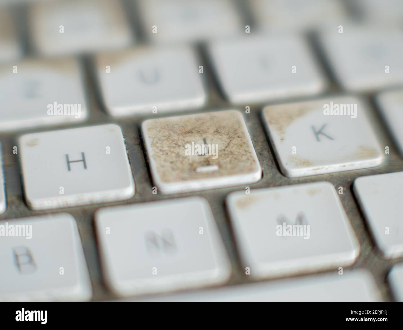 Very dirty white wireless computer keyboard with button J in focus Stock Photo