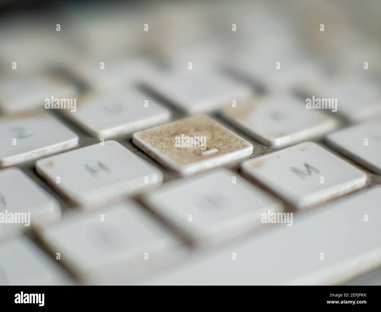 Very dirty white wireless computer keyboard with button J in focus Stock Photo