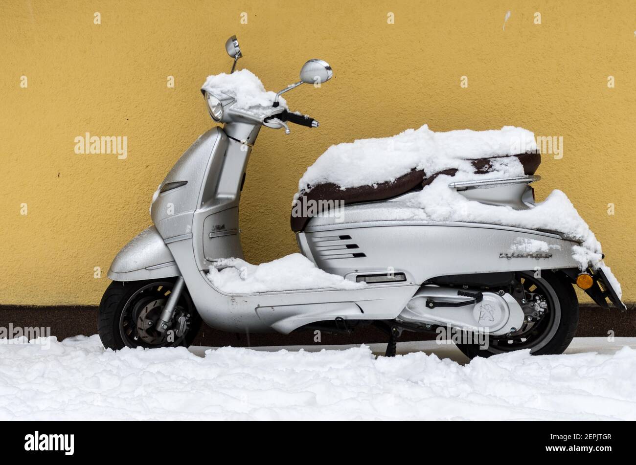 silver Peugeot Django scooter in snow, Warsaw, Poland Stock Photo