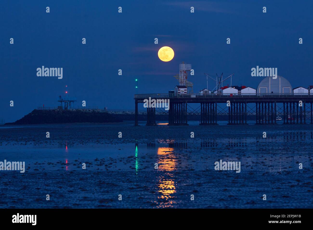 Herne Bay, Kent, UK. 27th February 2021: UK Weather. Full Snow moon just Waning Gibbous rises into a clear sky over Herne Bay pier at the end of a fine day, during the blue hour after sunset. Credit: Alan Payton/Alamy Live News Stock Photo