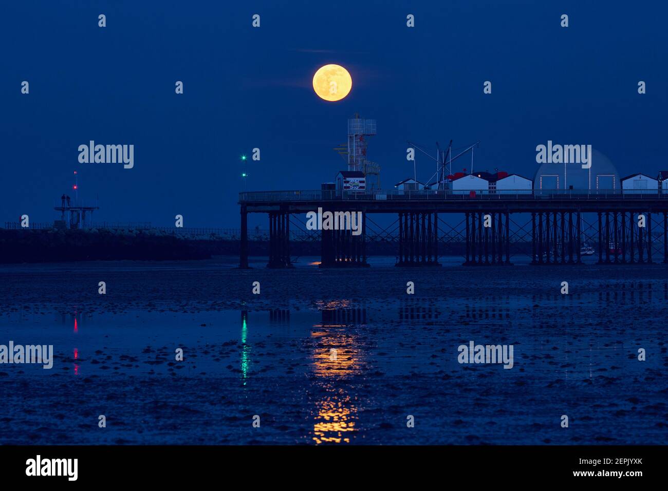 Herne Bay, Kent, UK. 27th February 2021: UK Weather. Waning Gibbous moon rises into a clear sky over Herne Bay pier at the end of a fine day, during the blue hour after sunset. Credit: Alan Payton/Alamy Live News Stock Photo