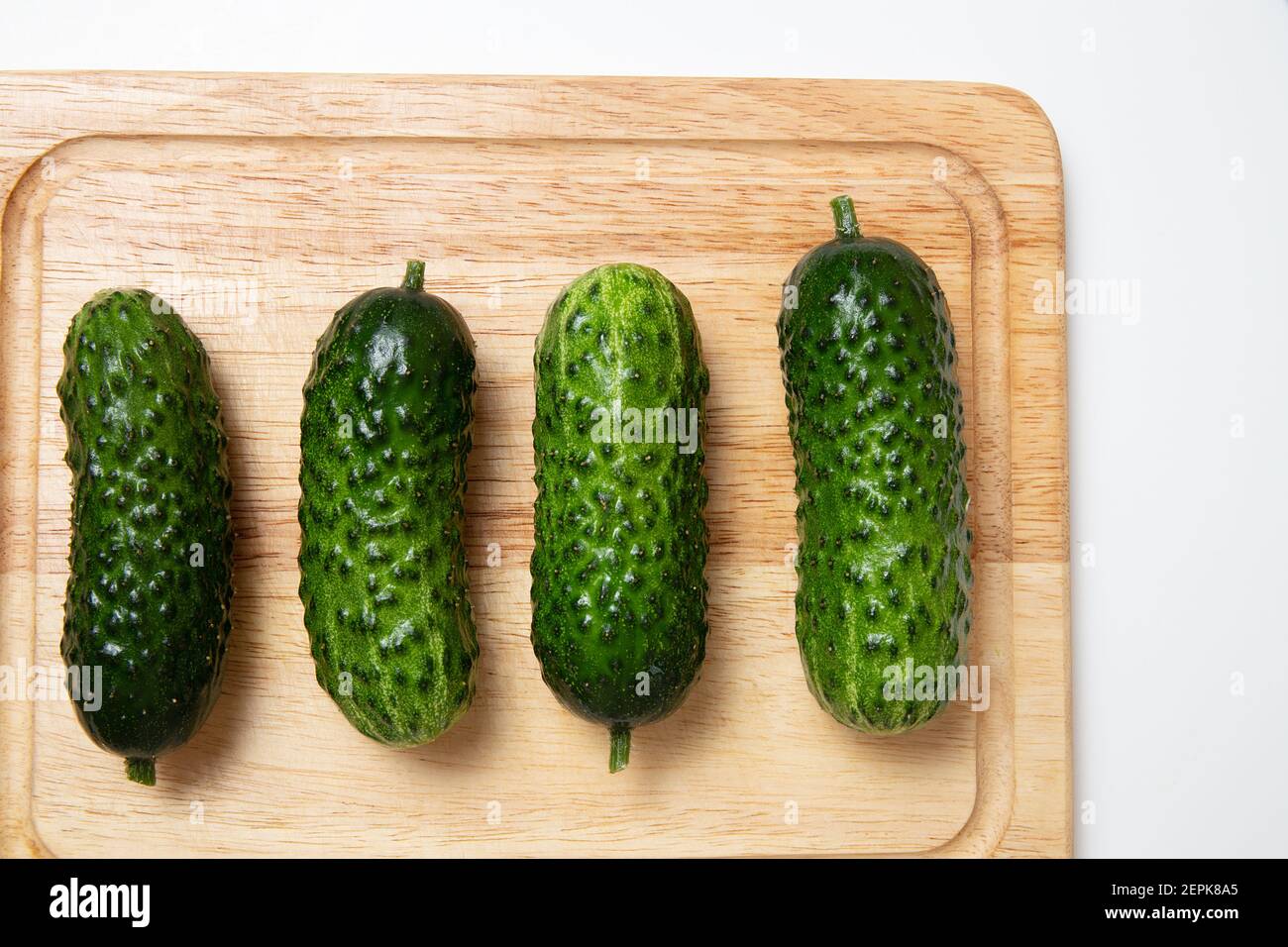 Group of green short cucumbers. Whole cucumbers on cutting board. Preparation ingredients for cooking or pickling Stock Photo