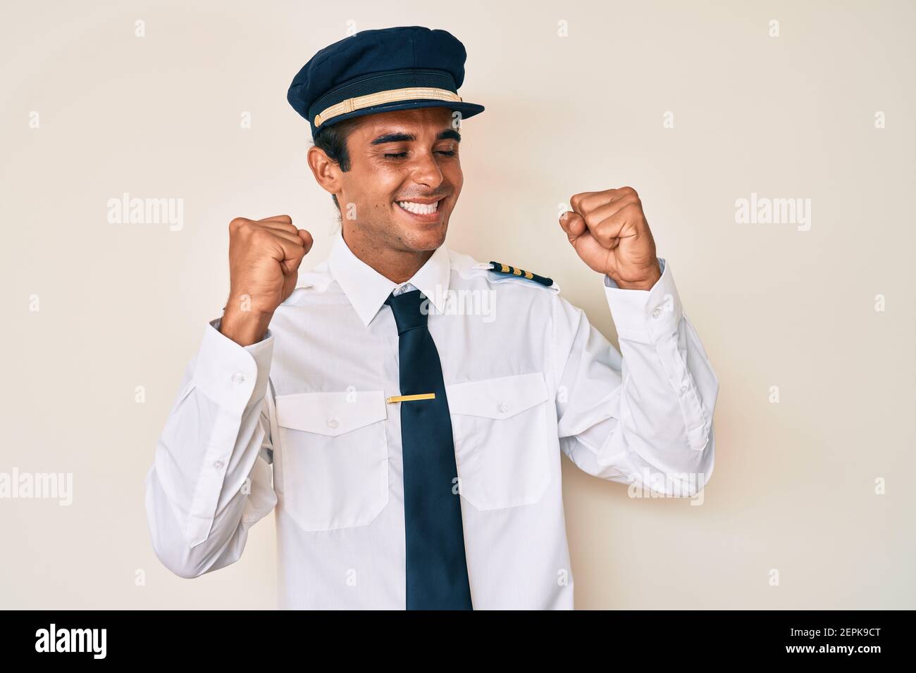 Young hispanic man wearing airplane pilot uniform very happy and ...